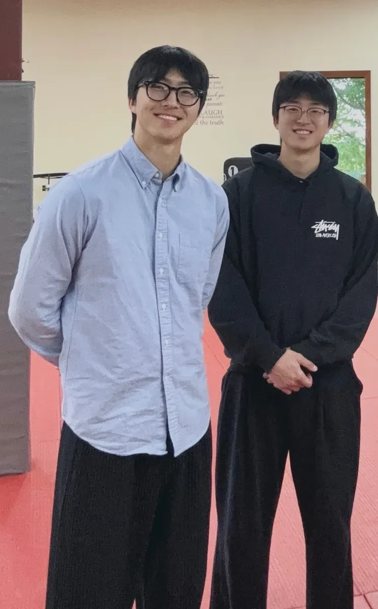 Two members of the TRUETH team standing together on the red mats of the academy, smiling