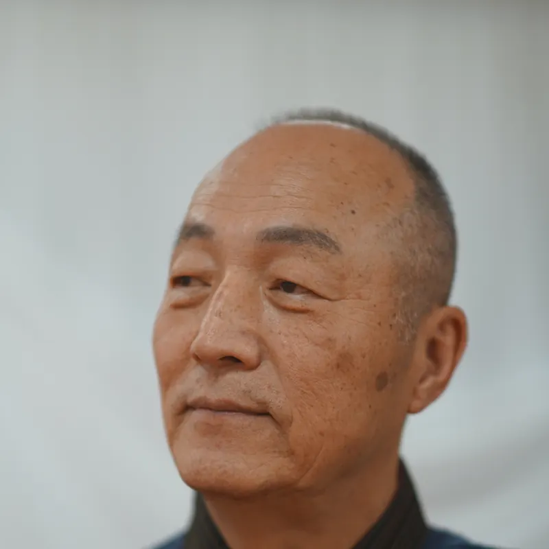Grand Master Won Kuk Kim looking to the side against a light backdrop