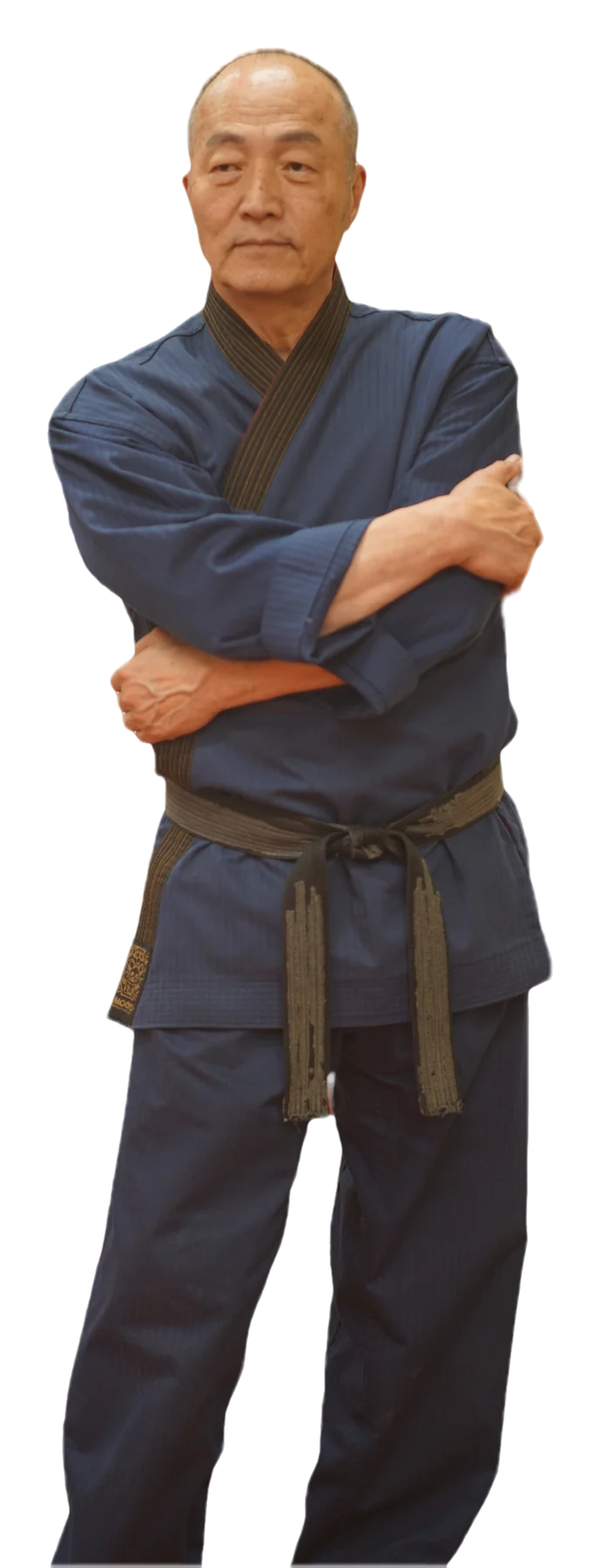 Grand Master Won Kuk Kim standing on the academy mats in his navy dobok and belt
